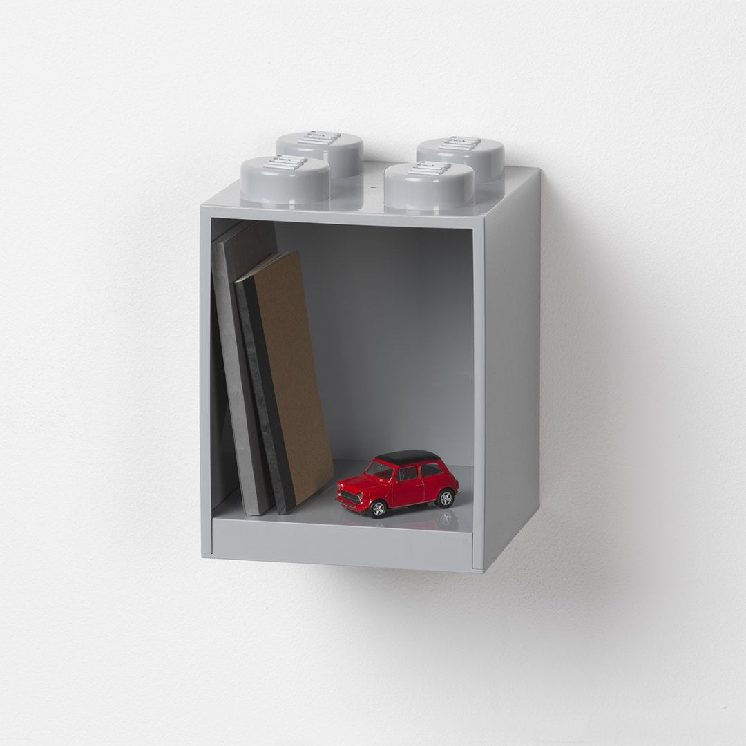 Nowoczesna półka LEGO szara w kształcie klocka z książkami i czerwoną zabawką samochodu