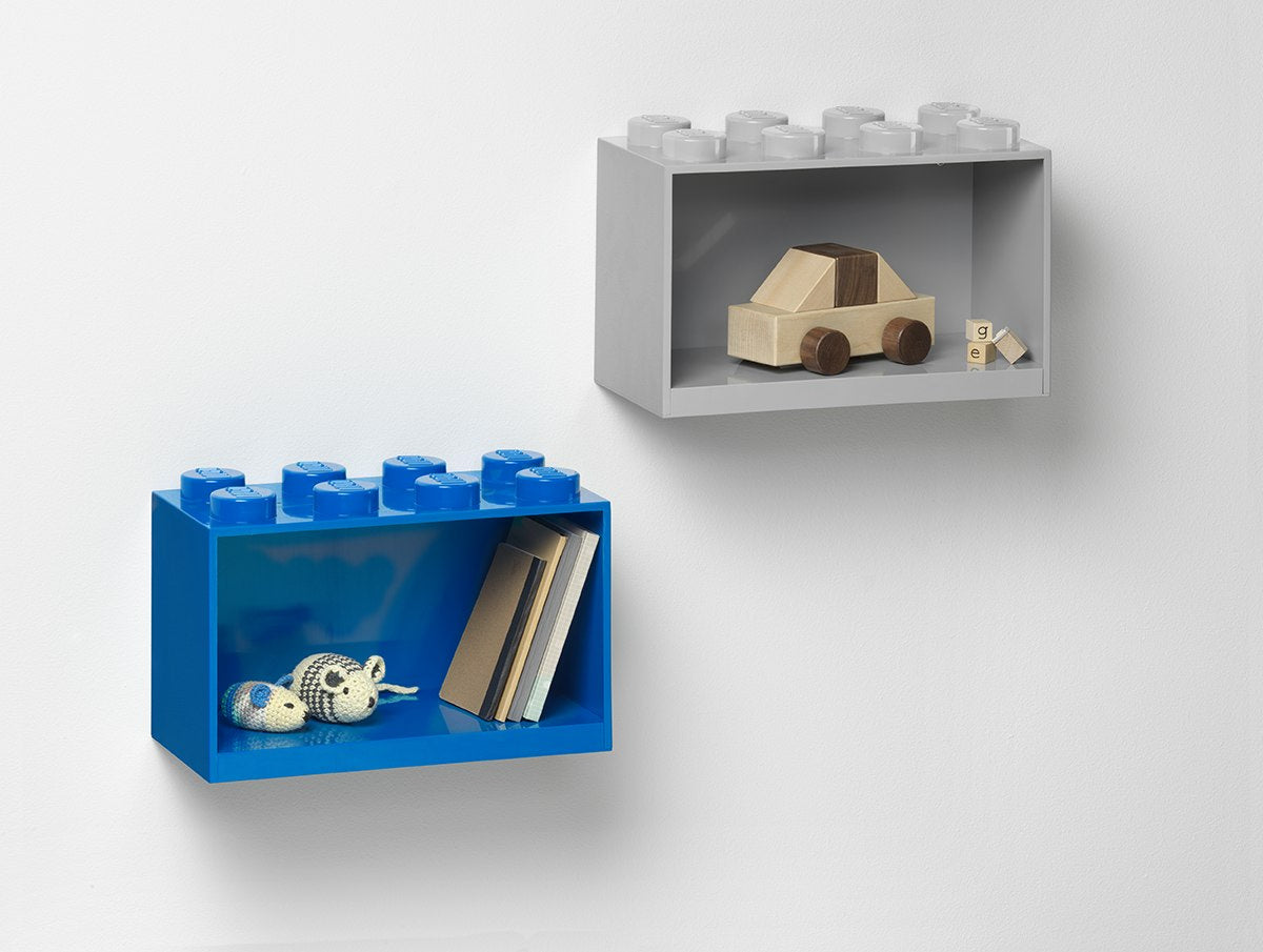 Nowoczesna szara i niebieska półka LEGO na zabawki w kształcie klocków na ścianie z drewnianą zabawką i książkami