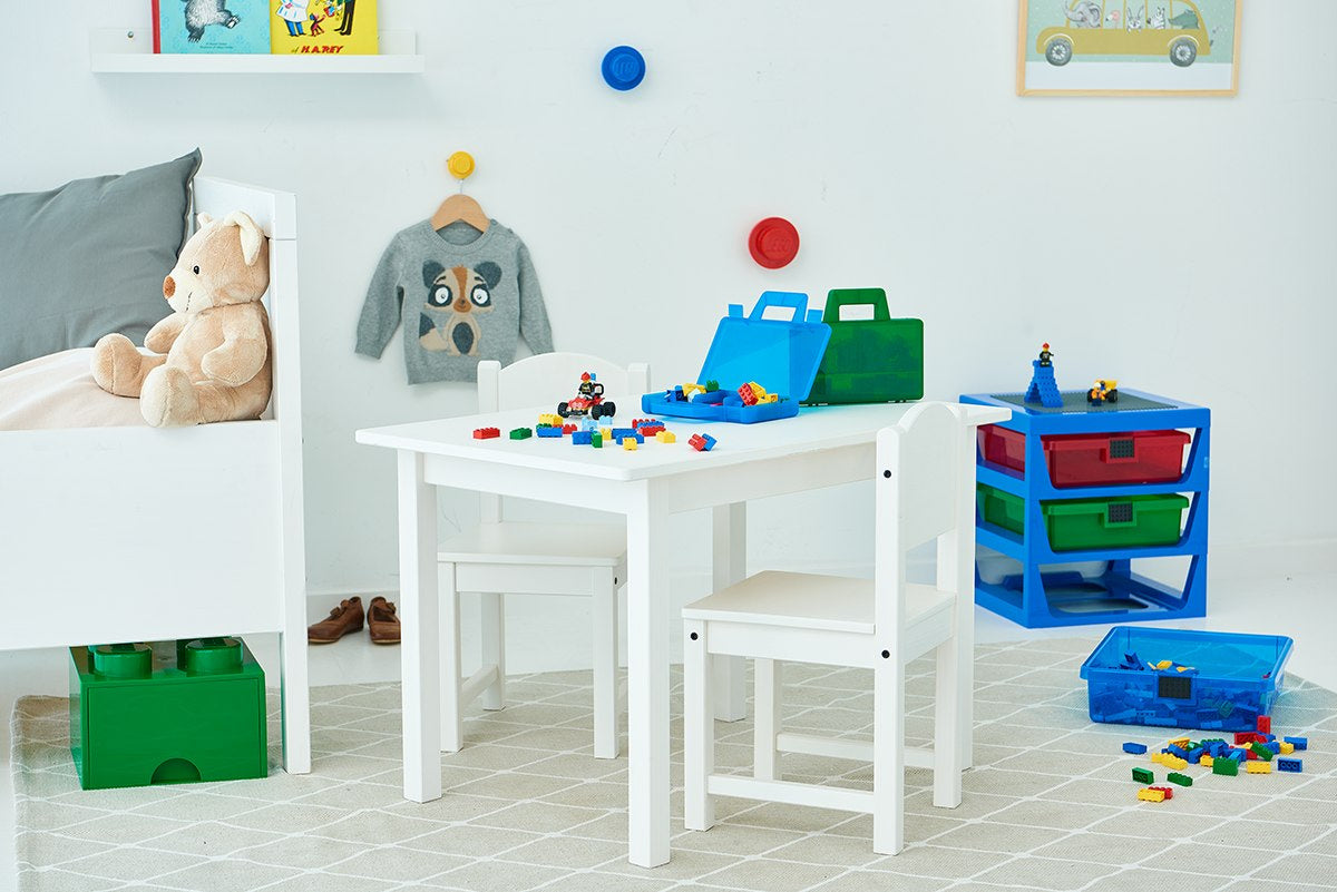 Dziecięcy pokój z białym stolikiem, krzesłami i kolorowym regałem LEGO z szufladami na zabawki