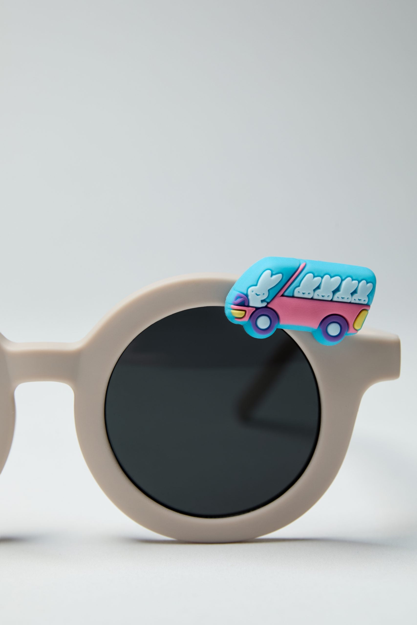 Beżowe okulary przeciwsłoneczne dla dzieci z ozdobą w kształcie niebieskiego autobusu z królikami
