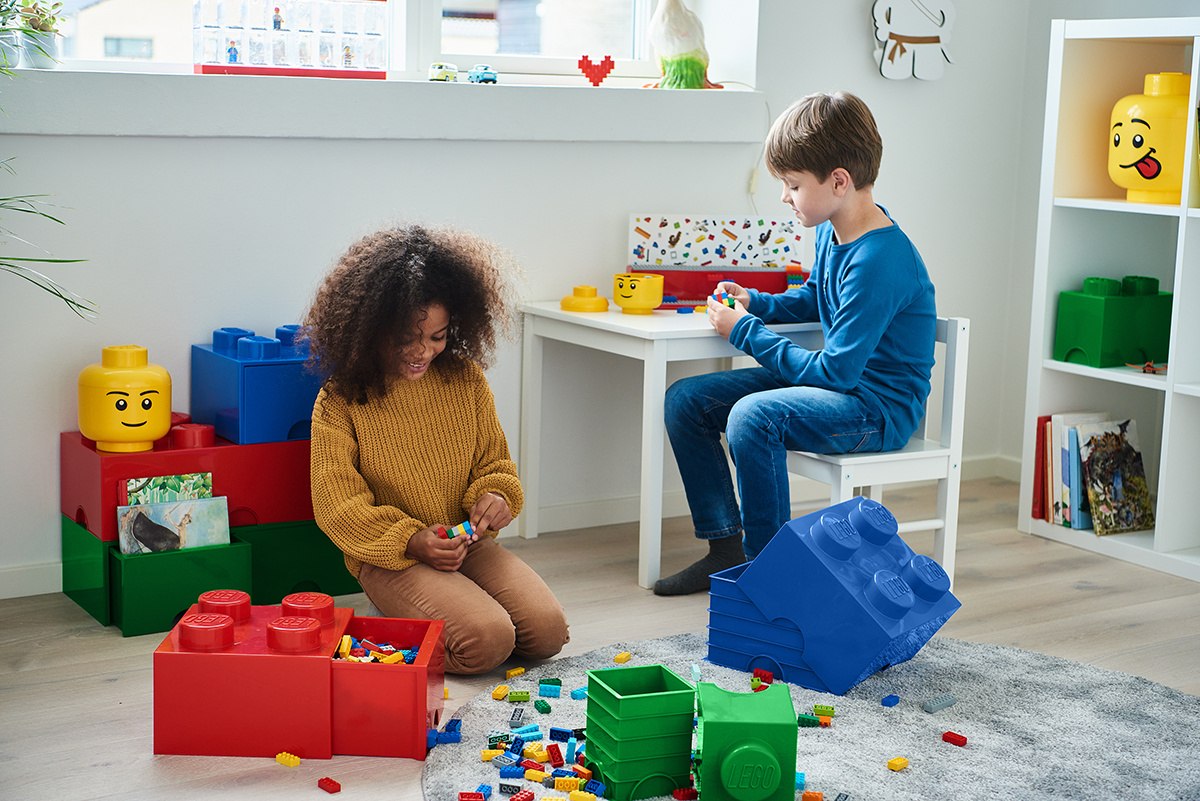 Dzieci bawiące się z szufladą LEGO Brick 4 czerwona w pokoju pełnym kolorowych klocków LEGO