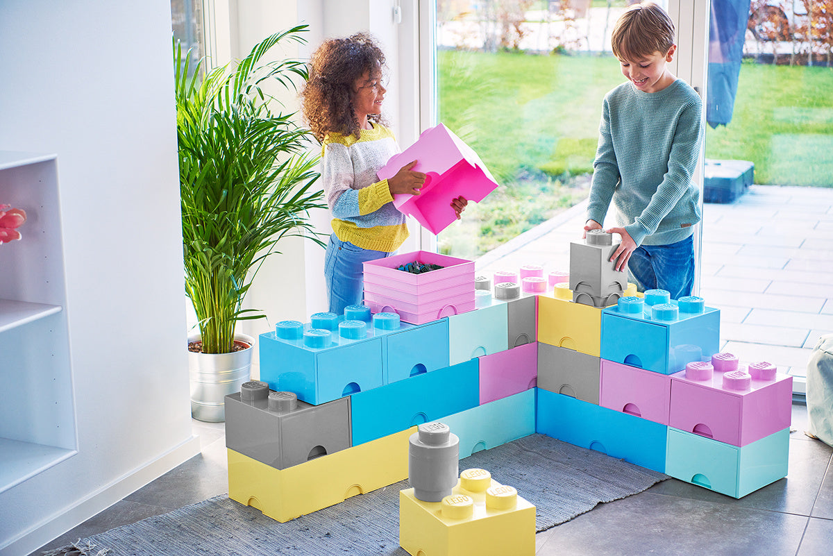 Dzieci bawiące się z szufladą LEGO na zabawki jasnoróżowa i innymi kolorowymi klockami w pokoju