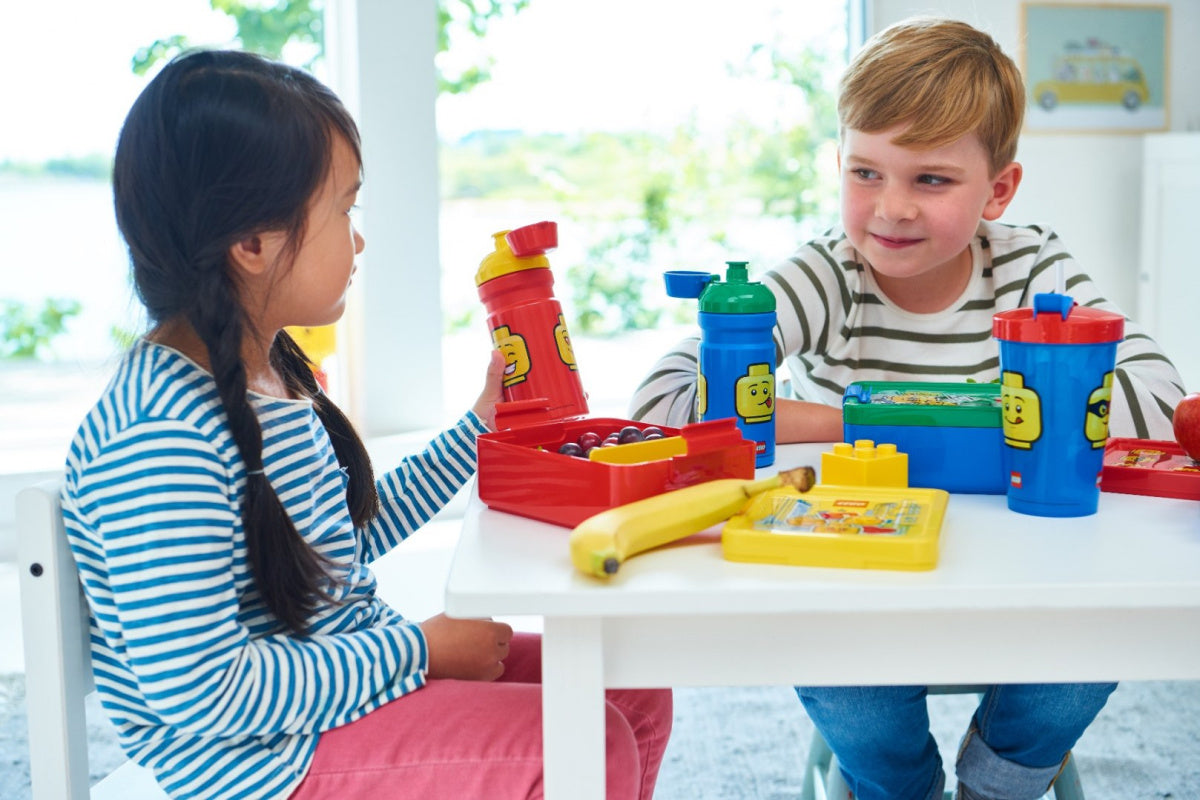 Lunchbox LEGO dla dziewczynki i chłopca podczas wspólnego jedzenia przy białym stole