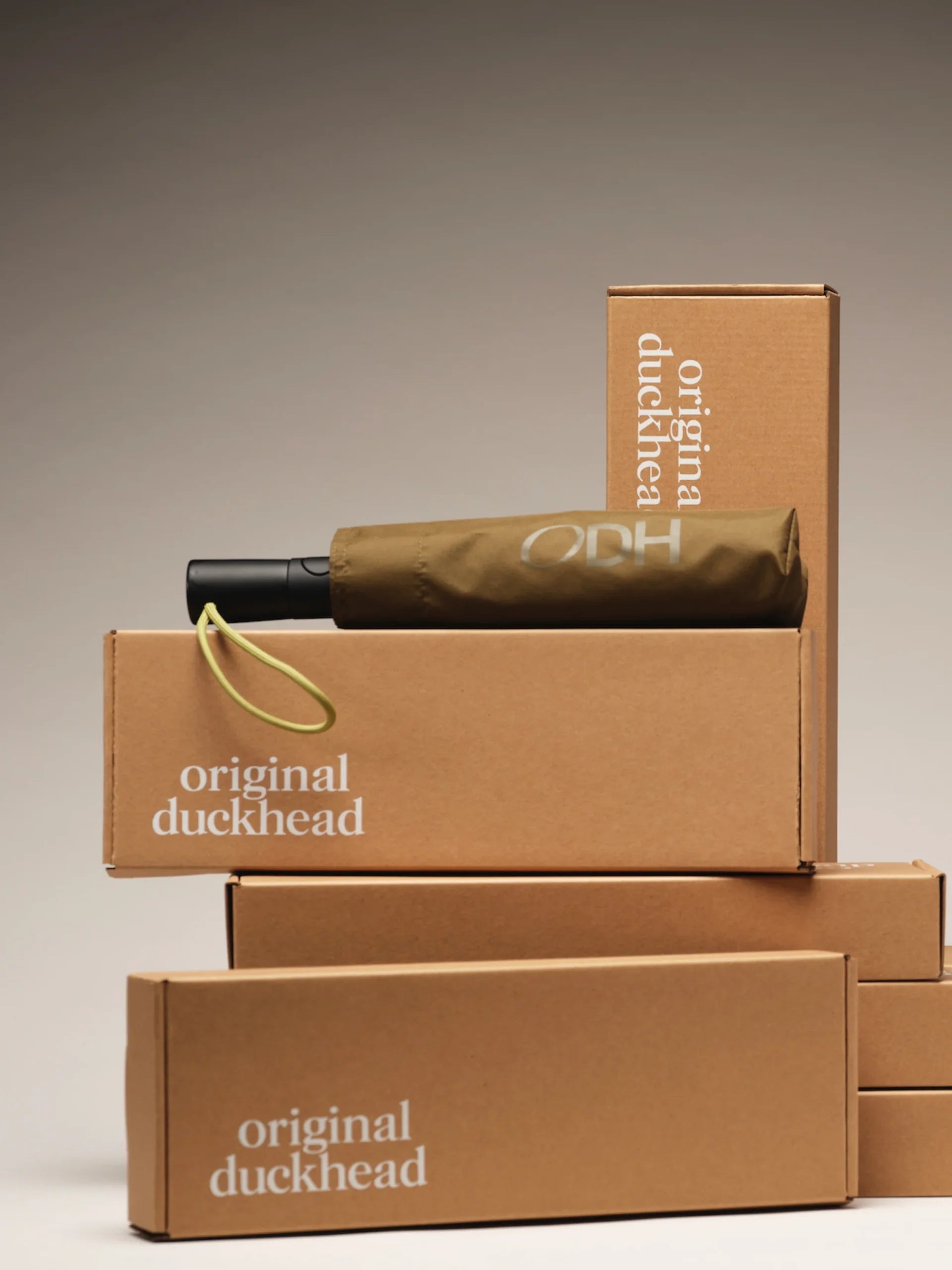 Parasolka automatyczna ciemna oliwkowa marki LOQI z pokrowcem na tle pudełek